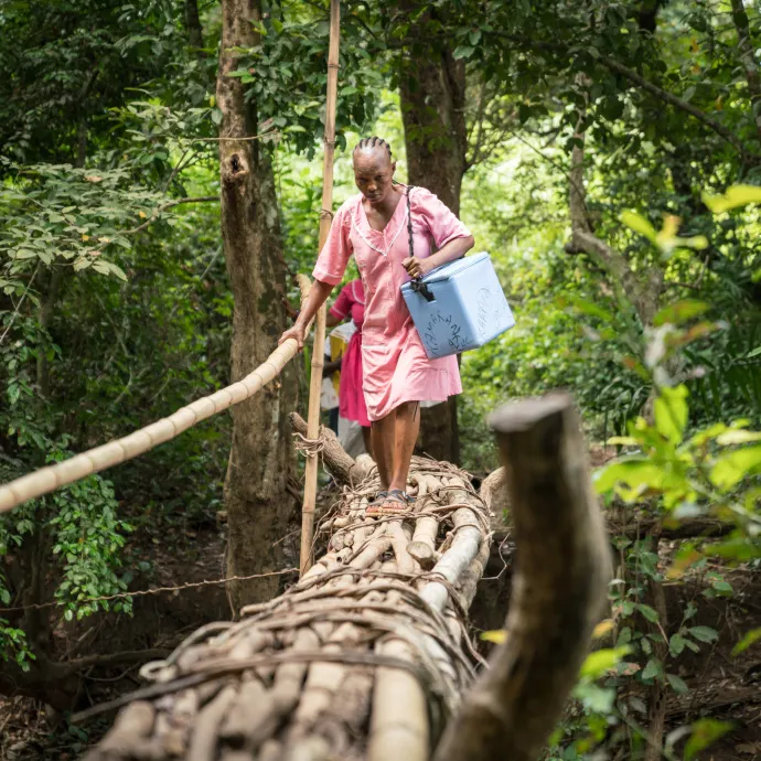 Nurse Isha crosses a bamboo bridge to reach the remote village of Mansunthu to conduct a mobile COVID-19 vaccine clinic. 